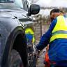 Tech working beside disabled vehicle on roadside.